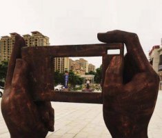 广场拿着手机照相的手景观铜雕